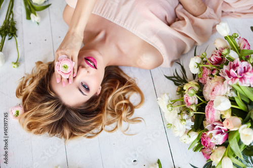 Portrait of a young blonde woman in flowers. Woman's face with make-up and hairstyle