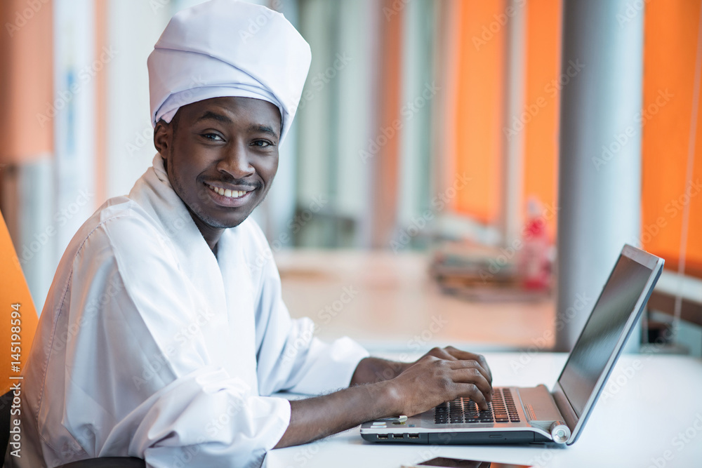 Sudanese business man in traditional outfit using mobile phone in office