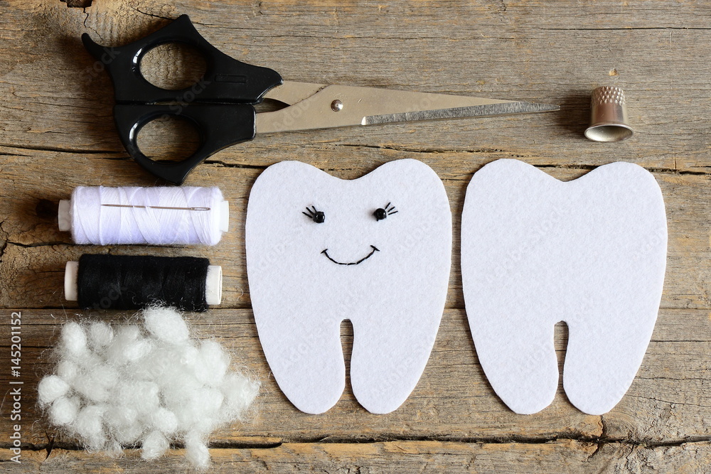 Fototapeta premium Making a felt tooth fairy. Step. Guide. On one side embroidered with black thread and beads eyes and mouth. Crafts supplies on vintage wooden table. Easy sewing diy for kids. Top view. Closeup