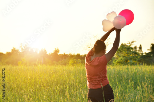 happy woman holding balloon in nature background at sunset.
