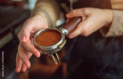 Closeup of female hand with the baristas Holder with freshly ground coffee.