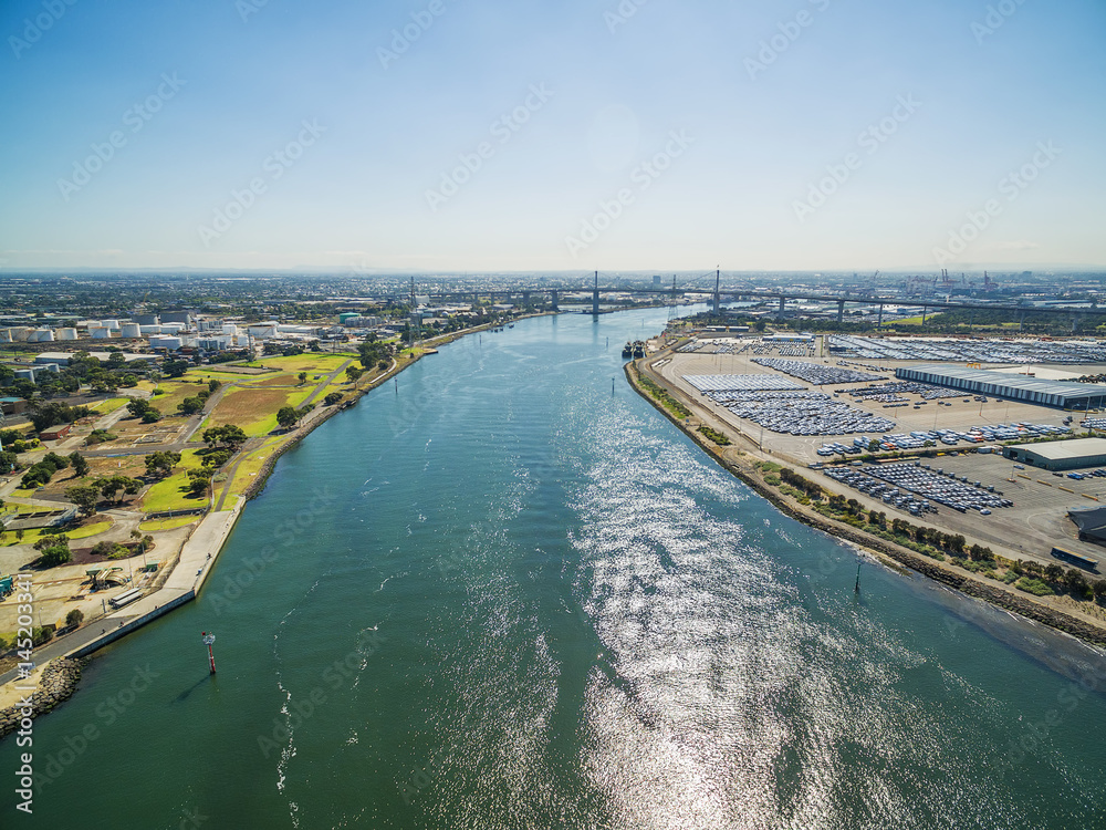 Aerial view of Yarra River, West Gate Bridge, and Melbourne International Roll on Roll off Automotive Terminal (MIRRAT) at high noon. Melbourne, Victoria, Australia.