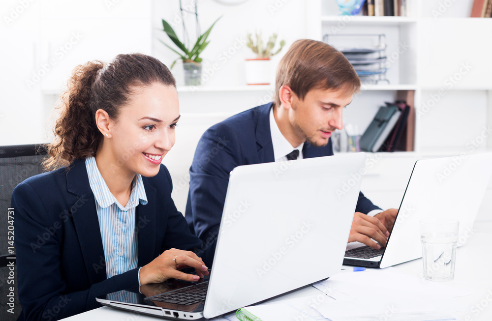 Obraz premium Two office workers work using laptops