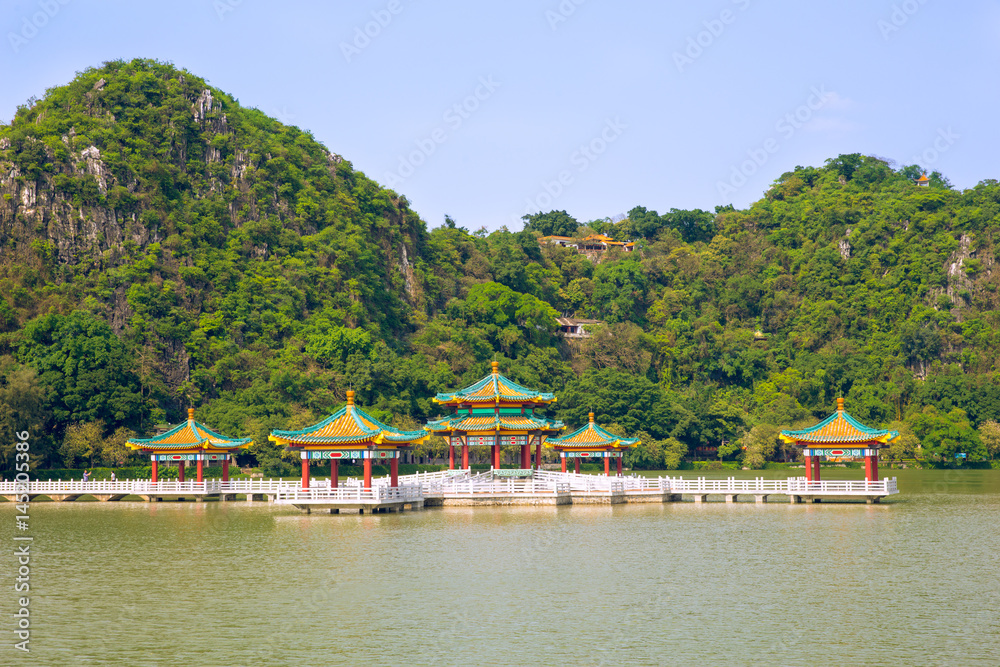 Complex of pavilion with traditional Chinese roofs on lake background mountain