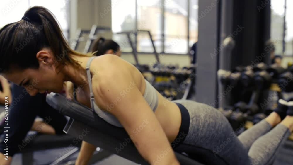 Young women in gym working out with various barbells Young women in gym working out with various barbells