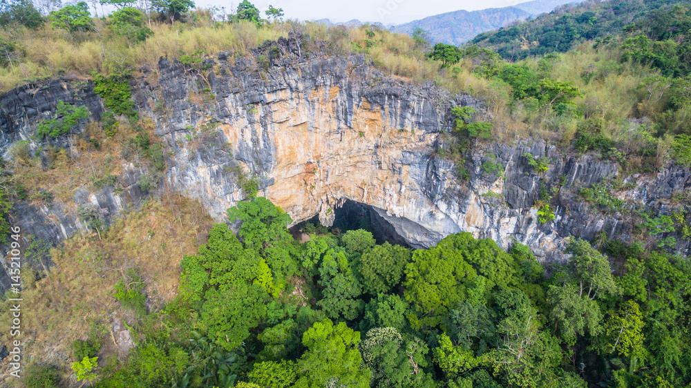 aerial photography above amazing cave. Tham Than Lod Yai is the big cave and have one hole on the top of the cave. it is a short cave there have waterfall pass inside through to another cave