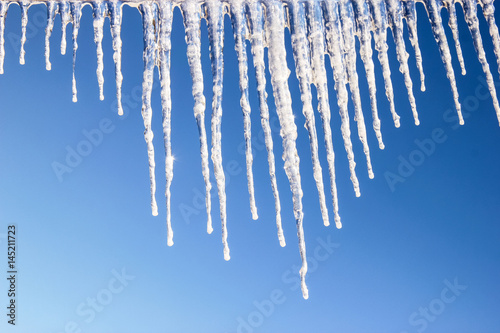 Icy icicles on blue sky background