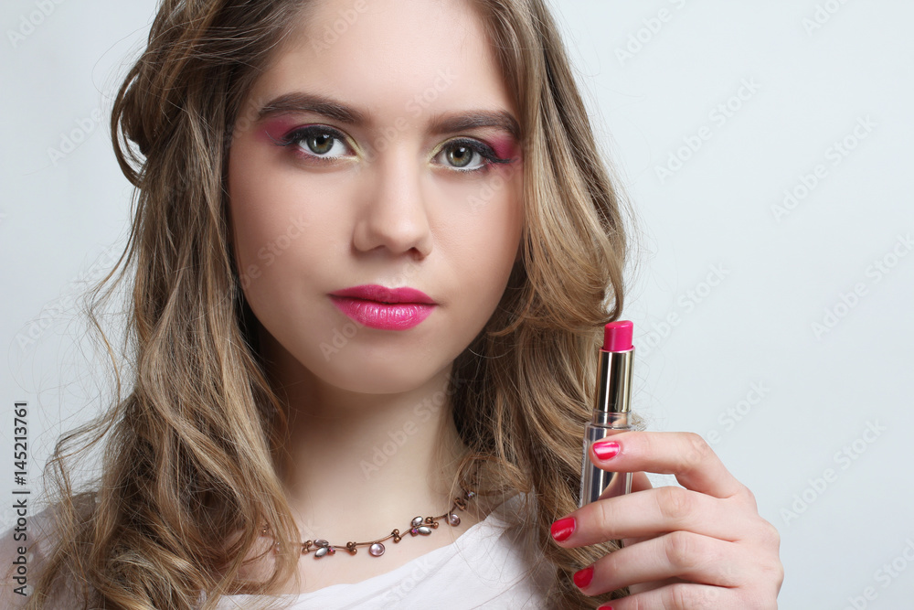 A young girl with a beautiful bright make-up is holding a lipstick A young girl with a beautiful bright make-up is holding a lipstick
