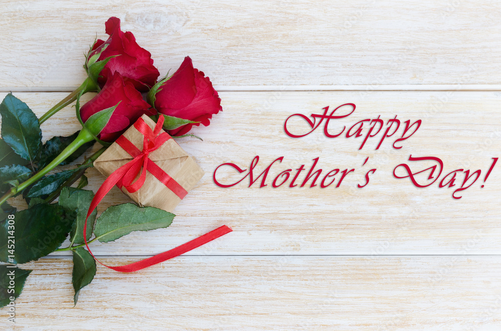 Fototapeta Bukiet kwiatów czerwonych róż i pudełko z wstążką i kokardą na drewnianym tle. Koncepcja karty z pozdrowieniami Happy Mother's day.