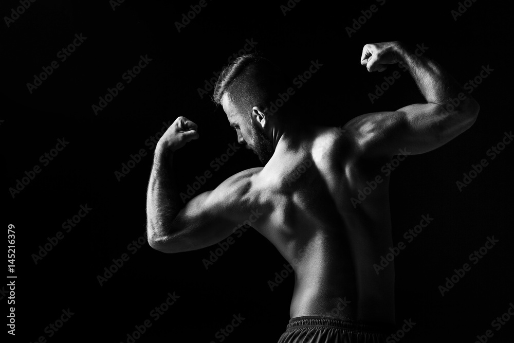 The back view torso of attractive male body builder on black background.