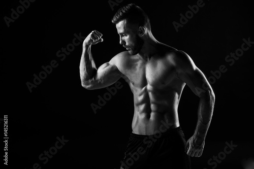 The torso of attractive male body builder on black background.
