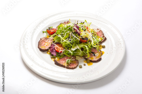 rucola salad and beaf on a white plate