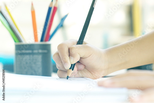 Little kid's hand drawing something on white paper.