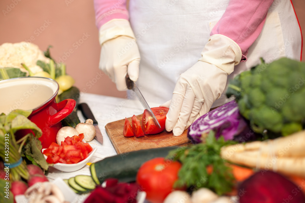 Woman with gloves cutting tomato Woman with gloves cutting tomato