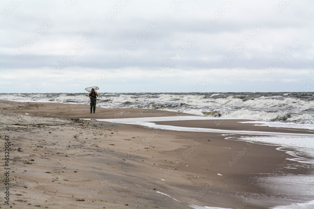 Lonely man on the beach. Amber gathering, stormy weather