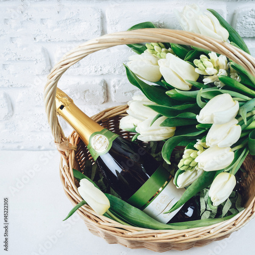 White basket with bottle of champagne and tulips