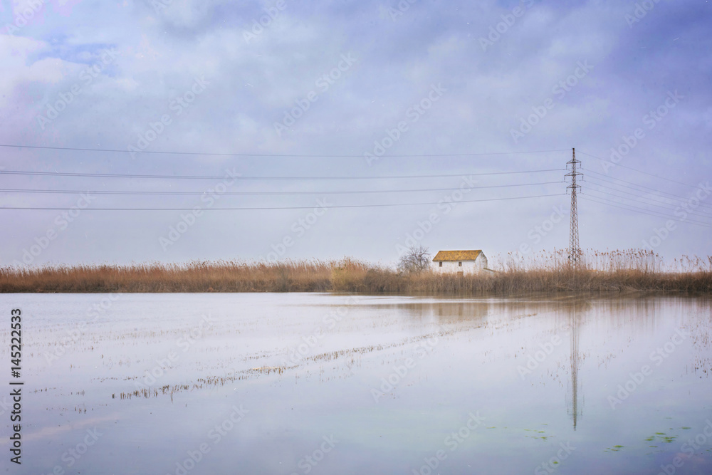 panoramic view of an isolated house in the middle of a lagoon surface in the albufera's park in valencia, spain panoramic view of an isolated house in the middle of a lagoon surface in the albufera's park in valencia, spain