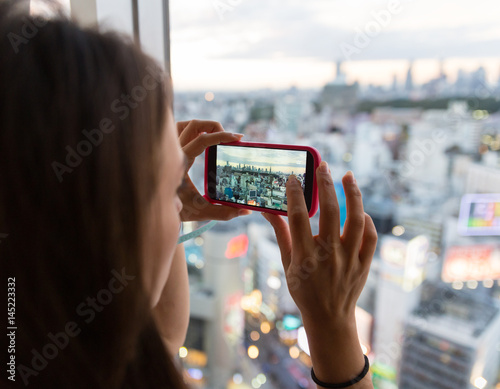 Photography A young woman taking a picture of the city from her hotel room