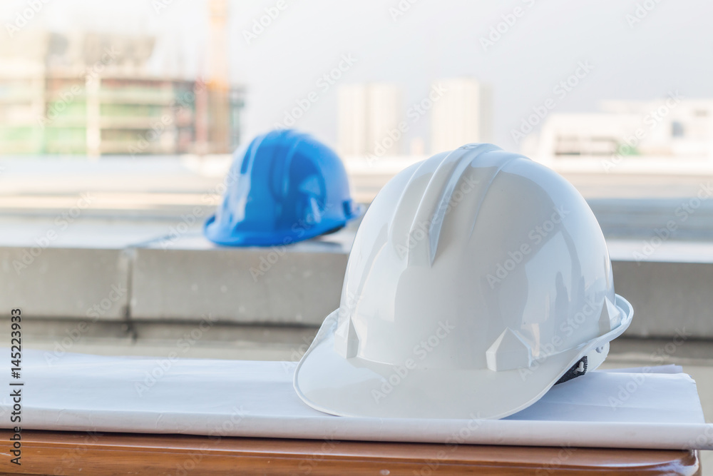 The white safety helmet at construction site with crane background The white safety helmet at construction site with crane background