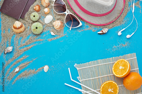 Summer background. Beach vacation accessories flat lay on sand with seashells and azure colour texture. Resort mood and relax holiday. 