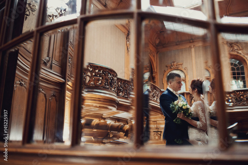 Reflection of hugging wedding couple in the mirror with wooden frame