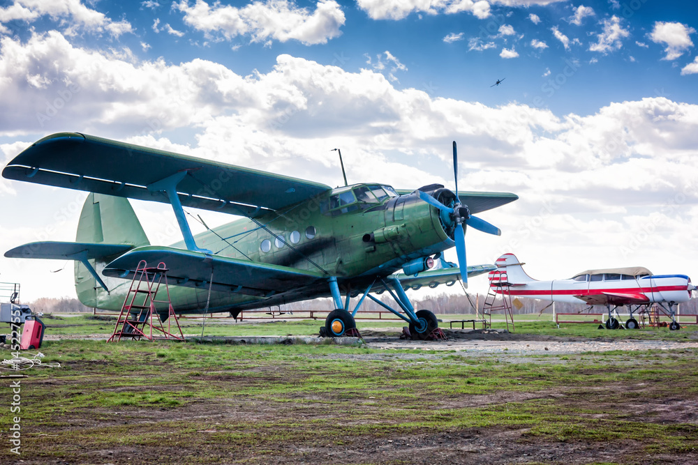 Retro passenger biplane and small sports airplane at the ground airfield Retro passenger biplane and small sports airplane at the ground airfield