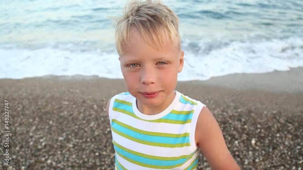 Funny little boy stands in front of camera and looks through old telescope with blurry beautiful sea waves background. 9 years old child enjoying nature on warm summer day. Real time video clip. Funny little boy stands in front of camera and looks through old telescope with blurry beautiful sea waves background. 9 years old child enjoying nature on warm summer day. Real time video clip.