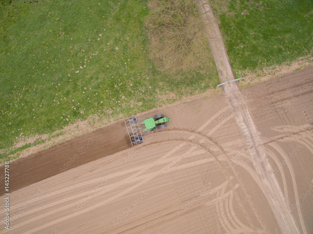 Fototapeta premium tractor - aerial view of a tractor at work - cultivating a field in spring - agricultural machinery