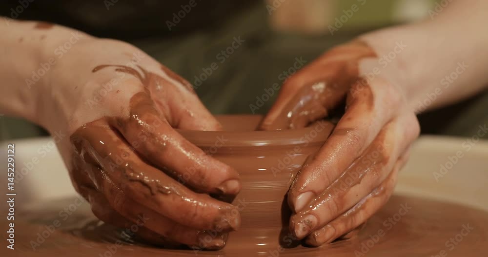 Close up of hands working clay on potter's wheel, close-up view Close up of hands working clay on potter's wheel, close-up view