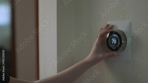 Woman Adjusting Smart Thermostat Gadget At Home