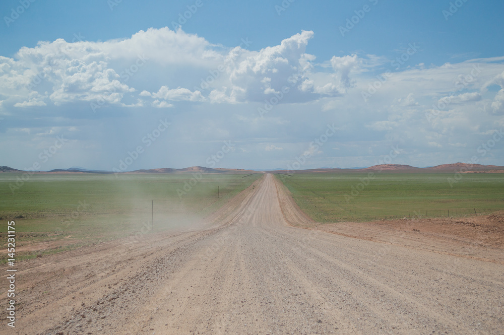 Scenic View of a Desert and Mountain Landscape after the Rain with Road and Dust Trail, near Solitaire, Namibia