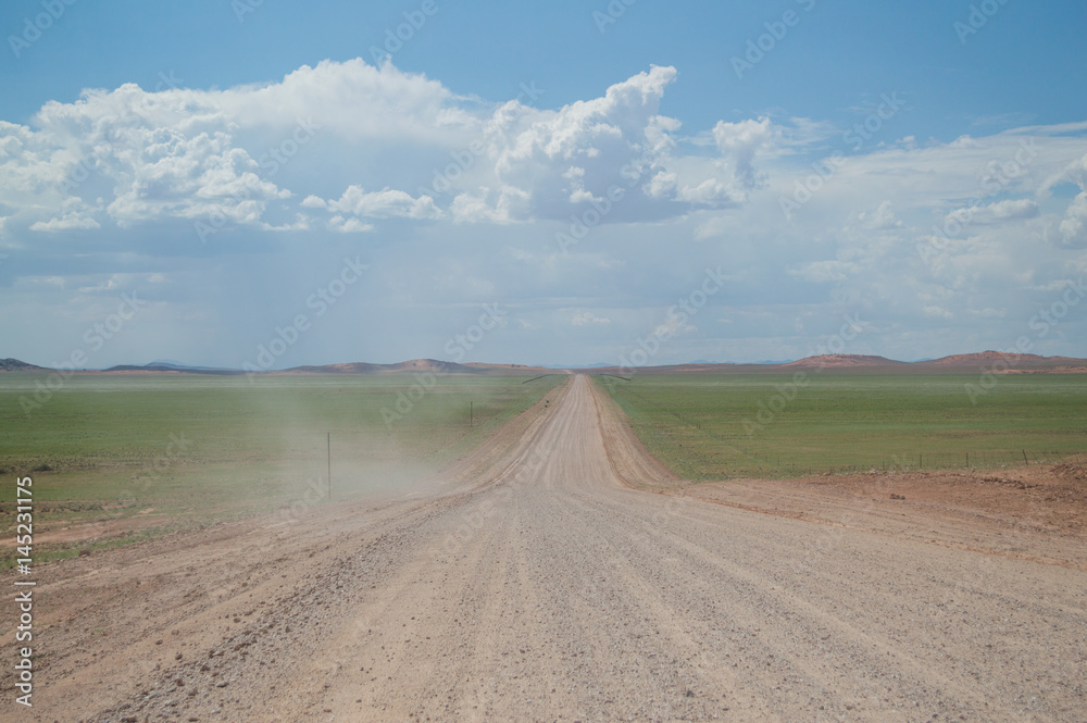 Scenic View of a Desert and Mountain Landscape after the Rain with Road and Dust Trail, near Solitaire, Namibia Scenic View of a Desert and Mountain Landscape after the Rain with Road and Dust Trail, near Solitaire, Namibia