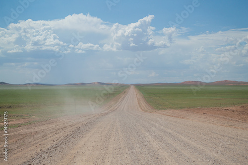 Scenic View of a Desert and Mountain Landscape after the Rain with Road and Dust Trail, near Solitaire, Namibia