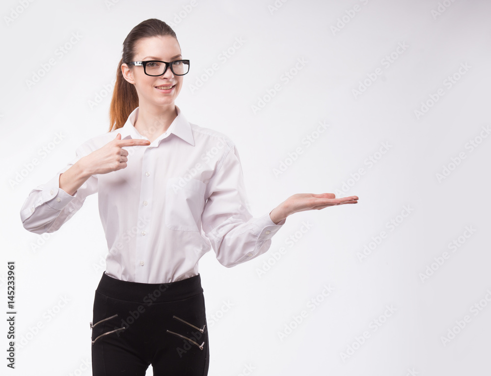 Young happy woman showing presentation, pointing on placard over gray background Young happy woman showing presentation, pointing on placard over gray background