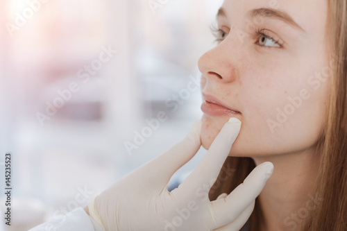 Proficient dermatologist examining patient face in the clinic