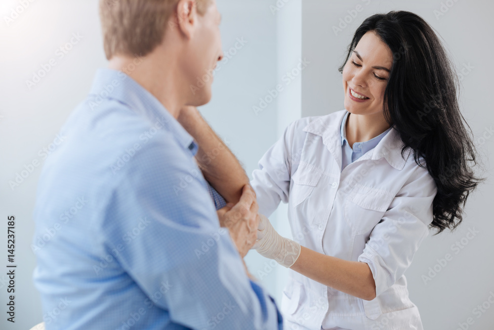 Cheerful practitioner enjoying helping patient in the hospital Cheerful practitioner enjoying helping patient in the hospital