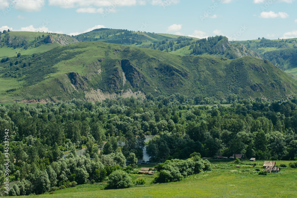 Huts built among the mountains and hills. Altai village, Russia. Landscape.