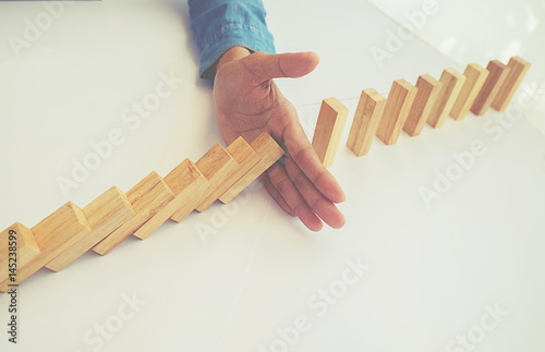 Problem Solving,Close up view on hand of business woman stopping falling blocks on table for concept about taking responsibility.