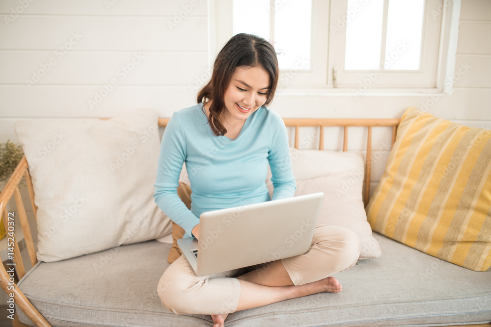 Happy casual beautiful asian young woman working on a laptop at home. Happy casual beautiful asian young woman working on a laptop at home.