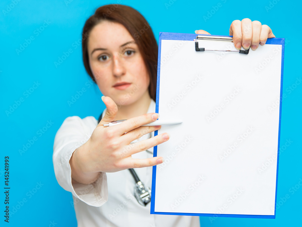 Young beautiful female doctor showing blank area for sign or copyspace, blue background Young beautiful female doctor showing blank area for sign or copyspace, blue background