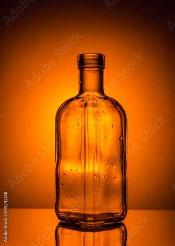 Bottle with drops on orange background