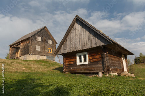 Two wooden village houses on a sunny onion. Carpathians, Ukraine