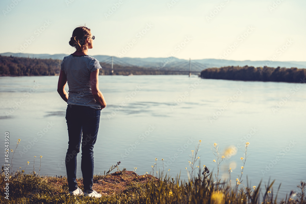 Fototapeta premium Woman standing by river