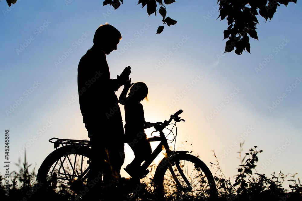 Obraz premium father and daughter riding bike at sunset