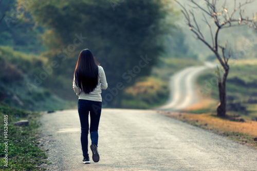 Women walk alone in the fall, the road is empty. photo