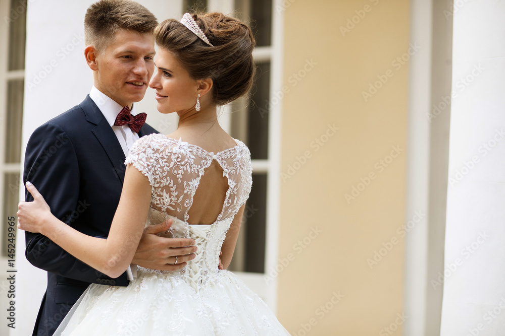 Bride and groom hold each other tender posing before white house