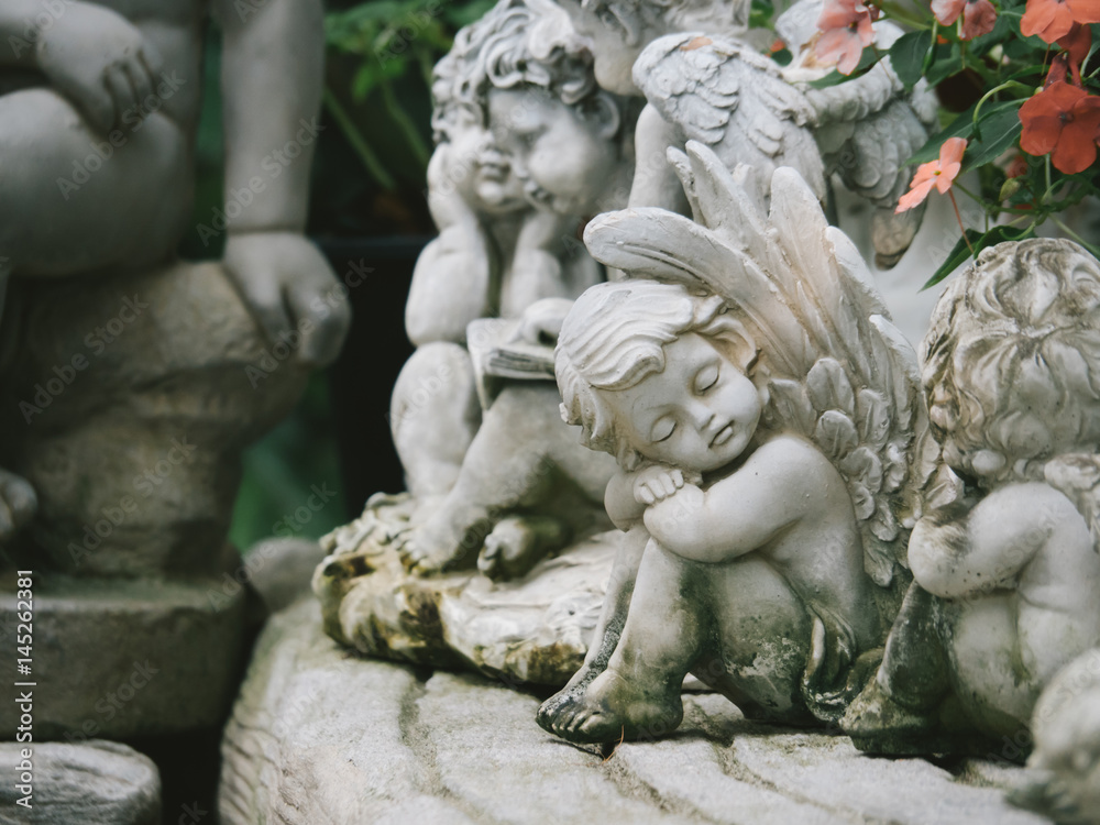 A white sculpture cupid in the garden, White cute cupid statue A white sculpture cupid in the garden, White cute cupid statue