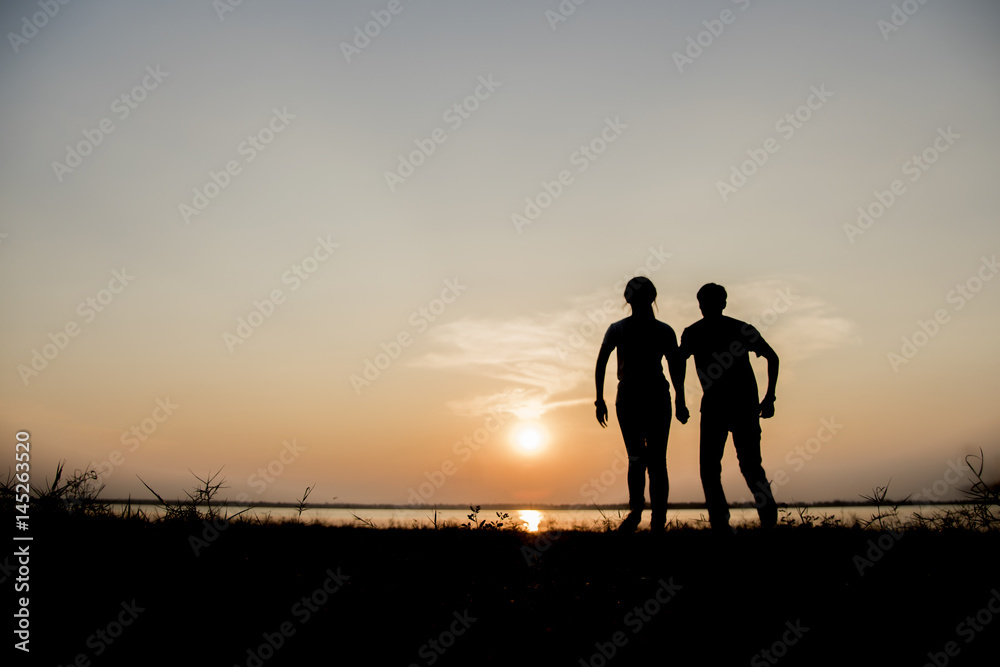 happy couple running on the beach on sunset