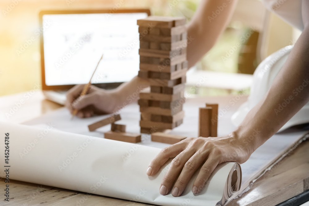 Obraz premium Projecting with pencil on the big urban drawings. Town planning and wood tower model for a architecture,architect working with vintage tone.