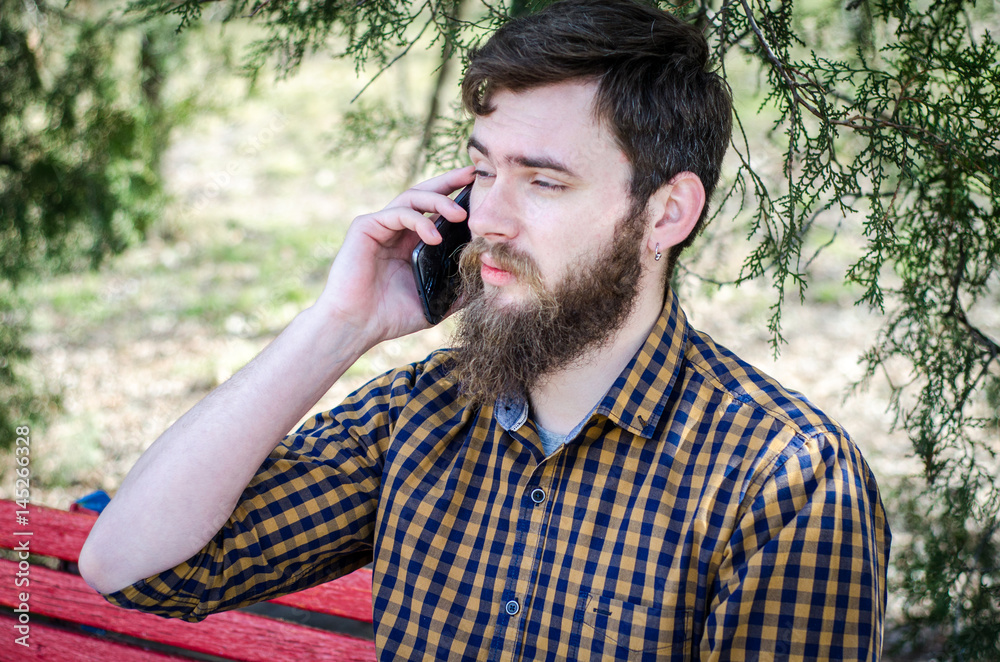 The guy speaks on the smartphone on the street The guy speaks on the smartphone on the street
